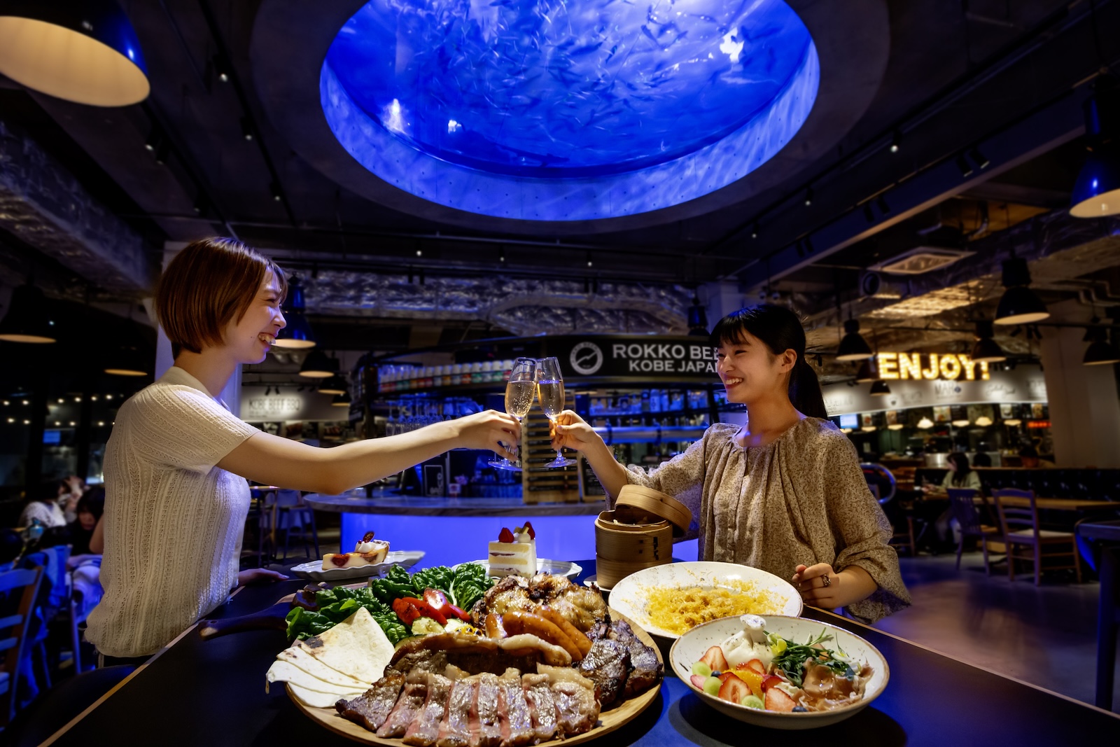 店内の巨大水槽を背景に乾杯する画像